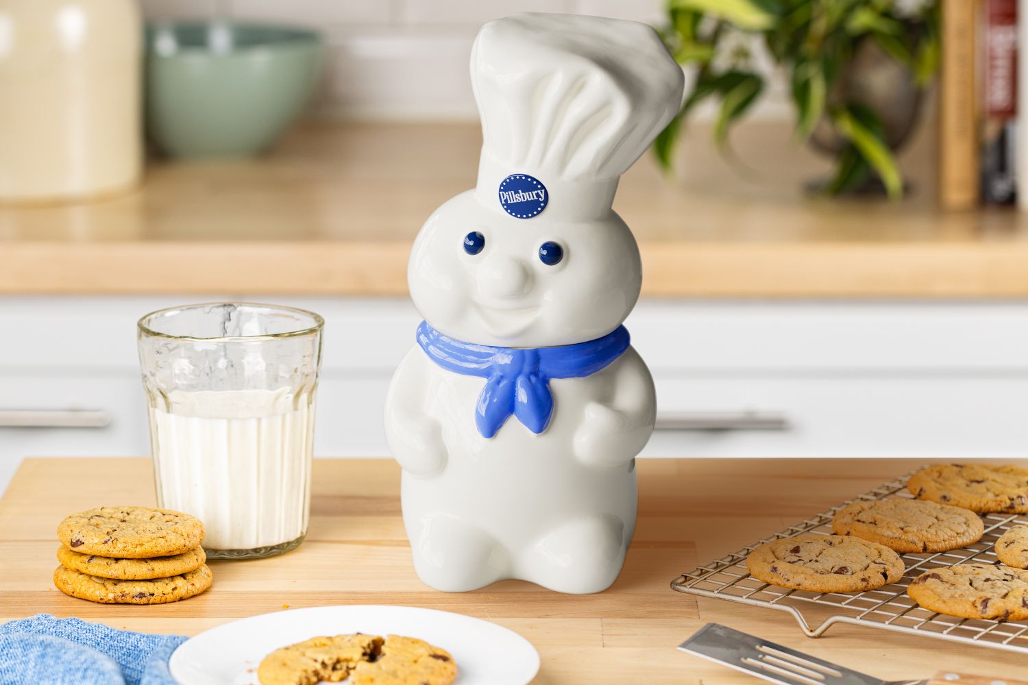 Doughboy cookie jar on a counter with cookies and a glass of milk