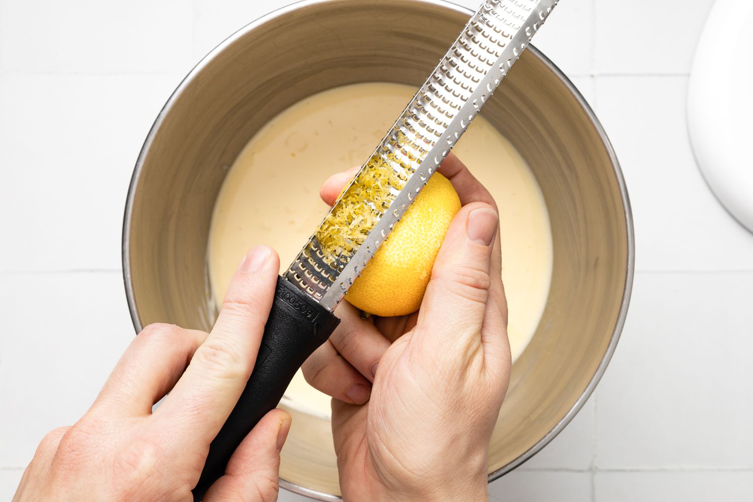 Lemon Zested Using a Microplane, and Underneath It, the Bowl With Lemon Cheesecake Bars Filling in a Mixer Bowl