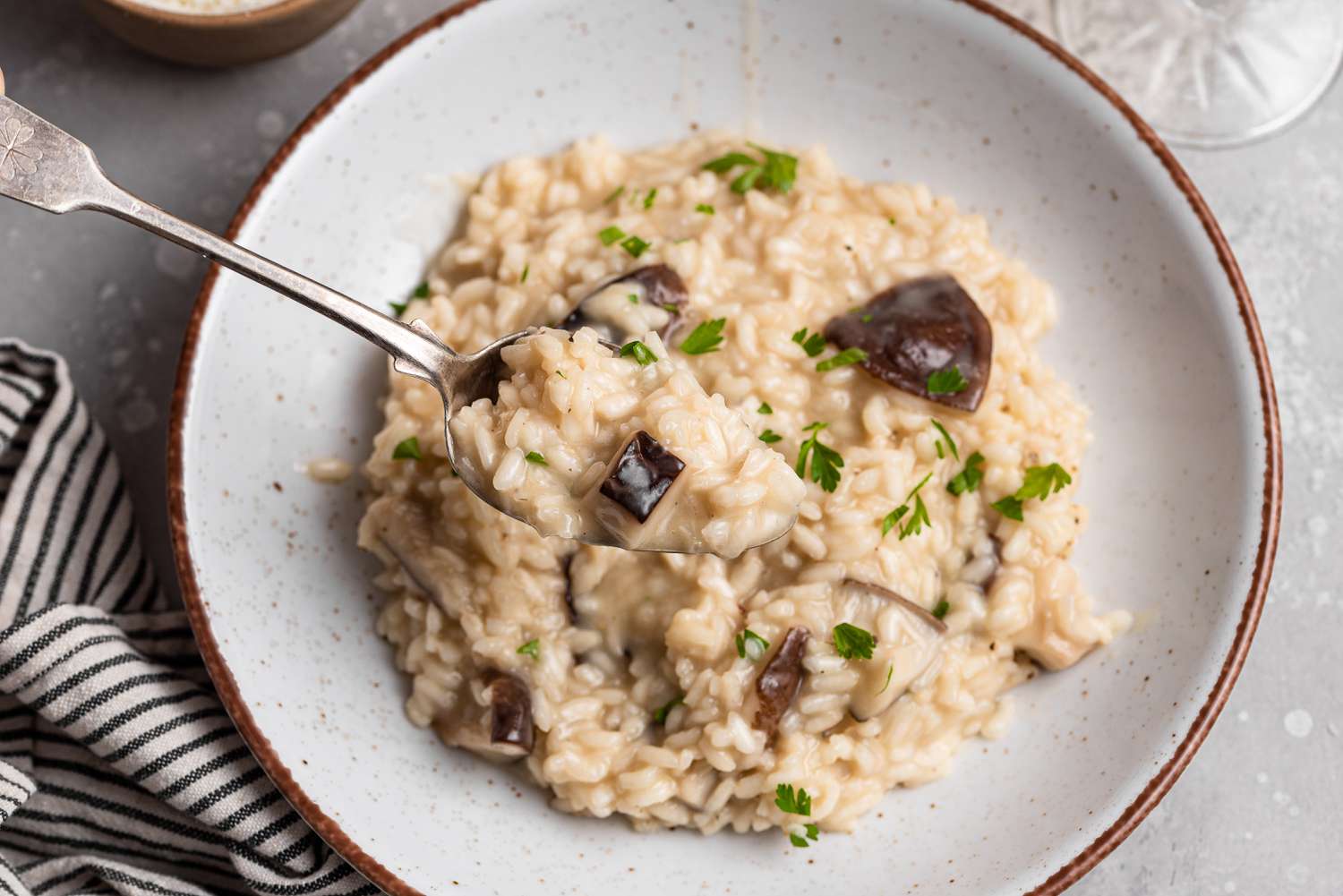 A bowl of mushroom risotto with a spoon scooping risotto out of the bowl.