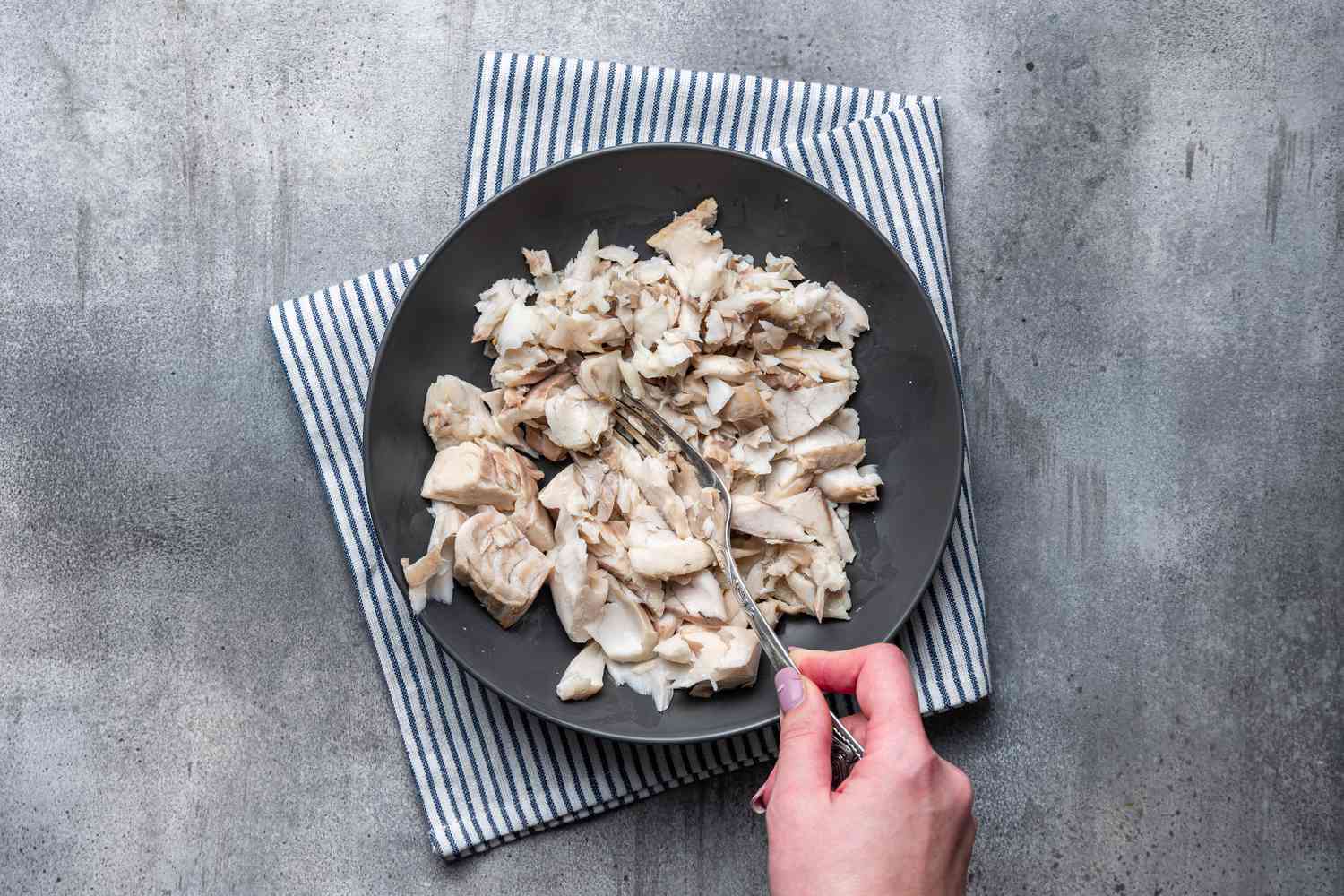 A plate of mashed cooked cod for Cod Fish Cakes