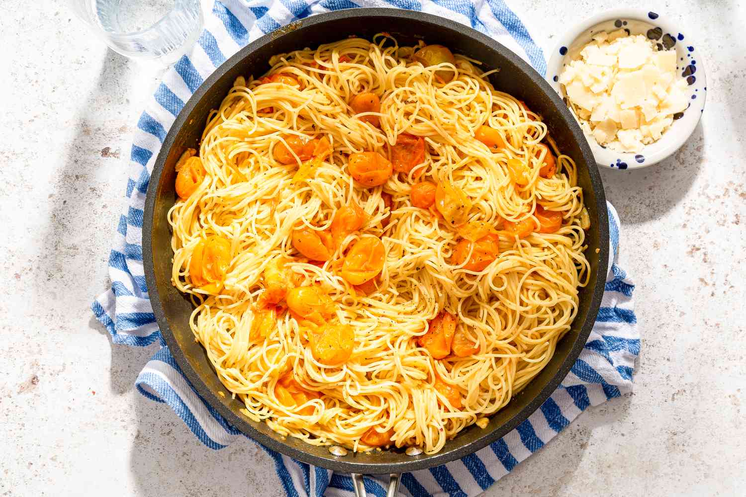 fresh tomato pasta in a bowl next to a bowl of shaved parmesan 