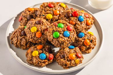 Plate of no-bake m&m cookies next to a glass of milk