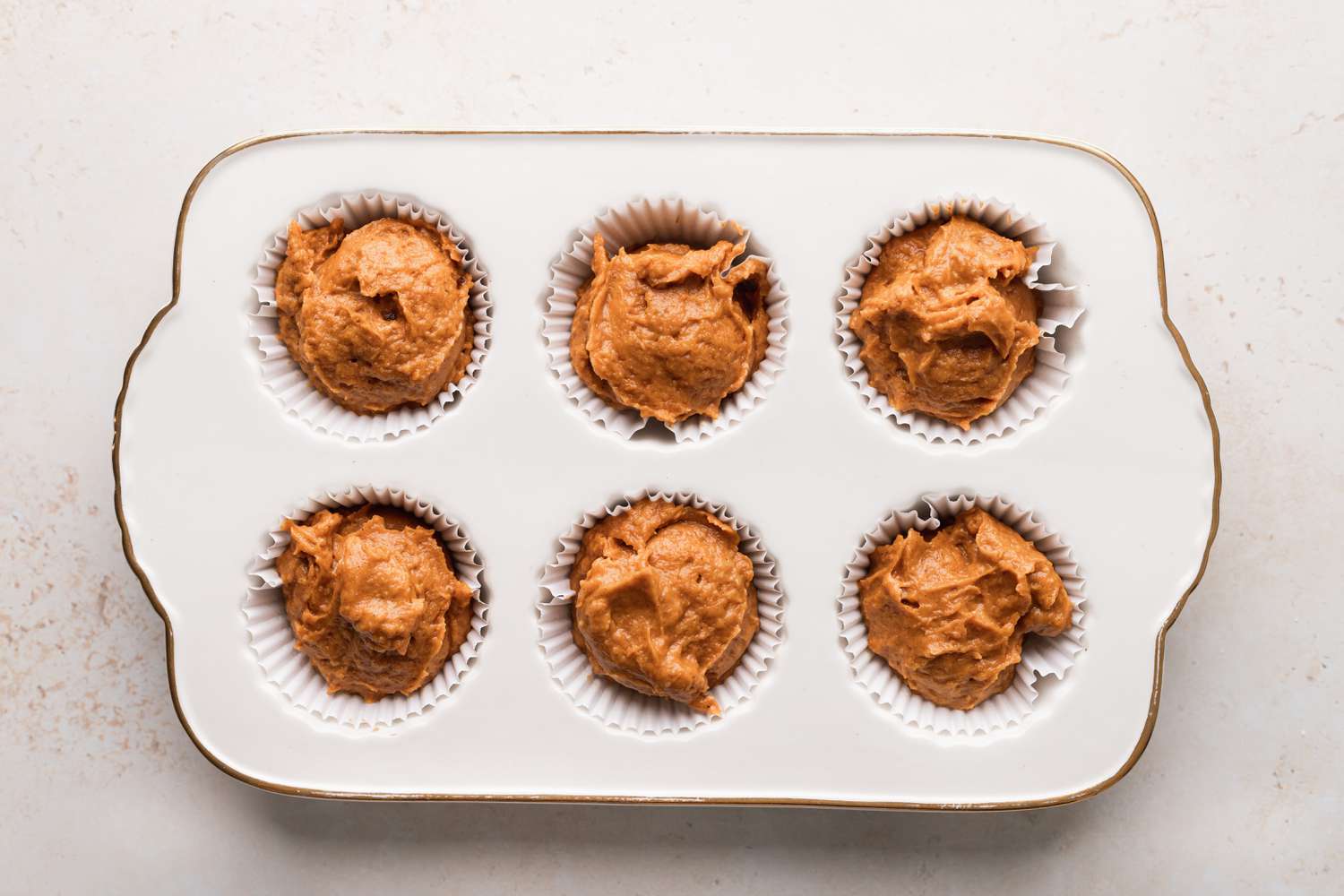 Pumpkin muffin batter in muffin tin.