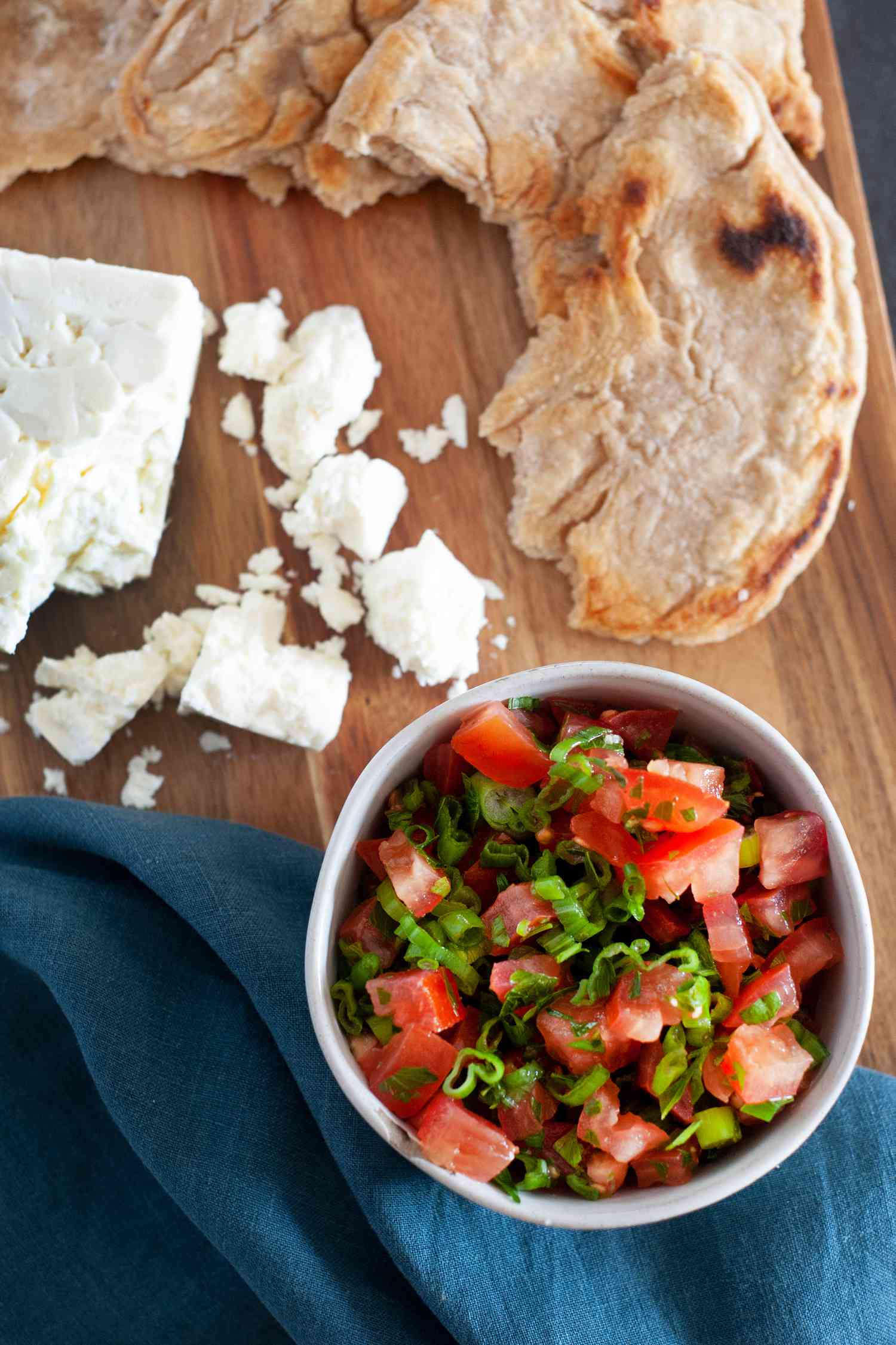 East African Tomato Relish in a bowl with flat bread and crumbly cheese above it.