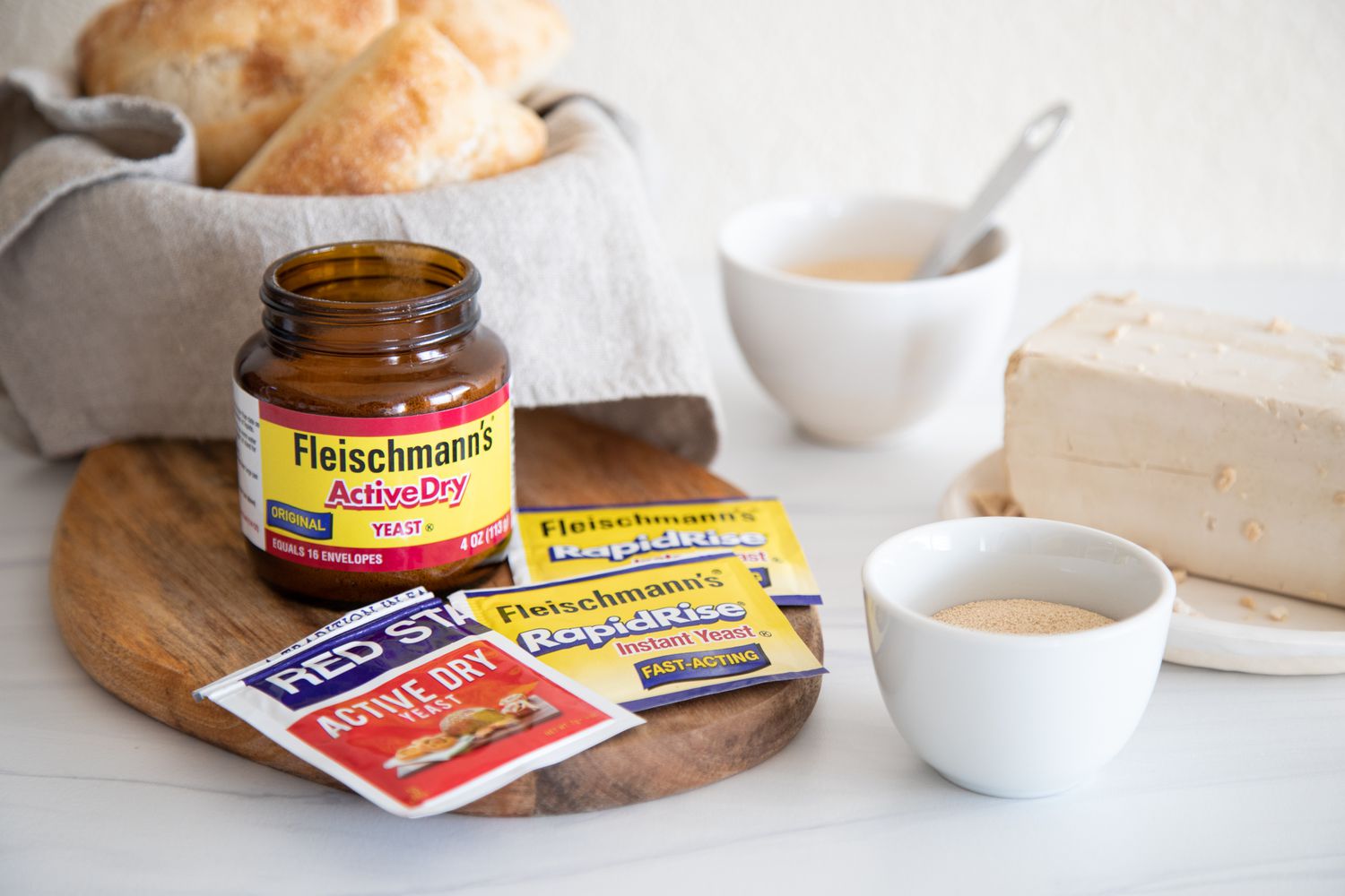 Side view of different types of yeast and a bowl with bread behind them.