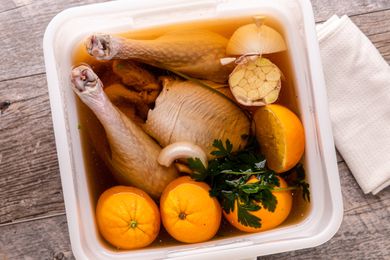 Brined whole turkey in a bucket with brining liquid.