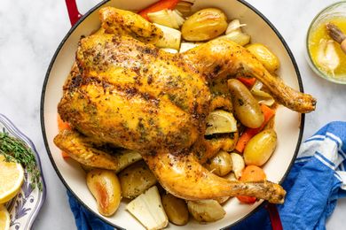 Cooked roast chicken in a dish with potatoes and vegetables