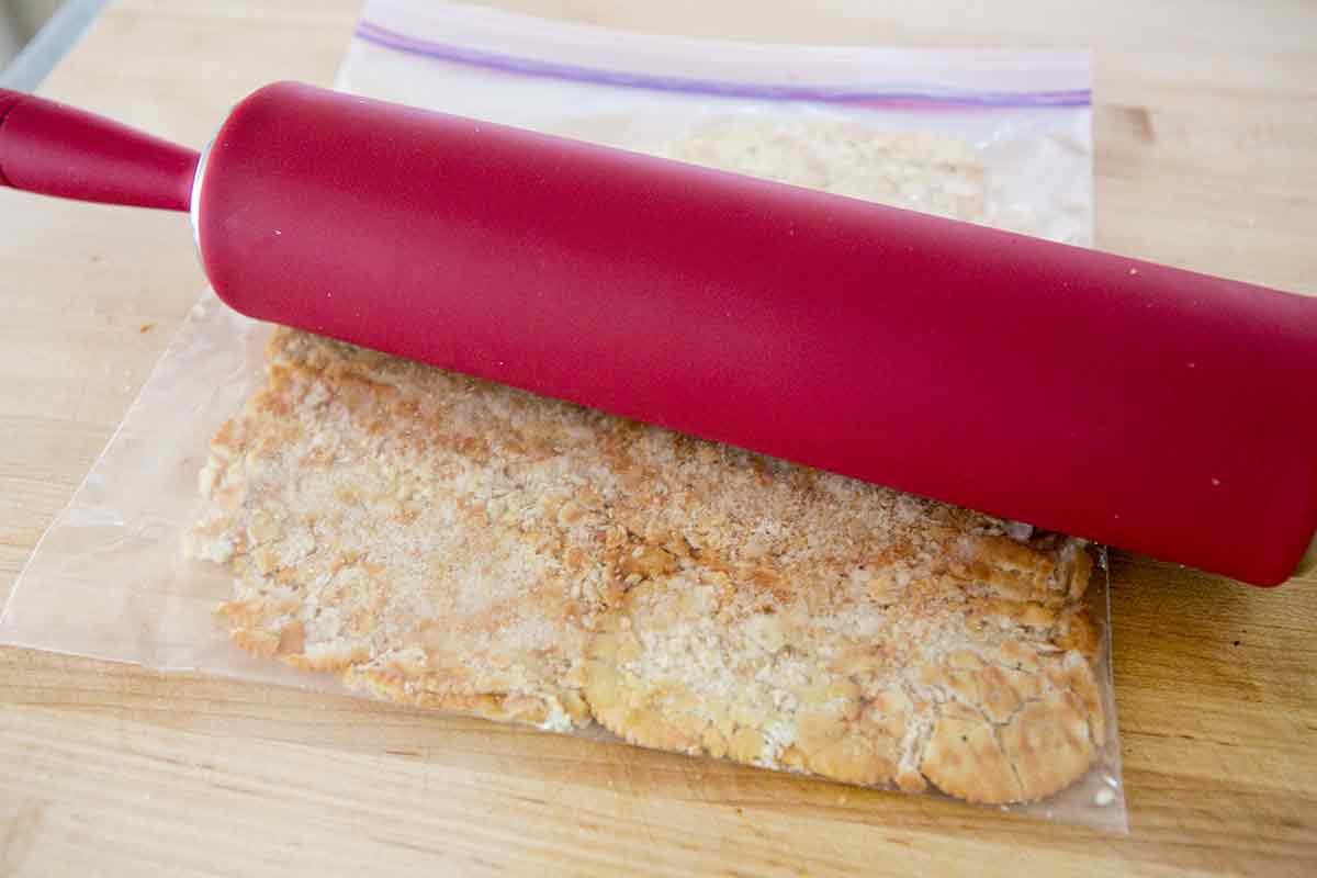 Rolling pin over bag of ritz crackers for baked cod topping