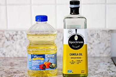 Bottle of vegetable oil on the left and a bottle of canola oil on the right (both on a counter)