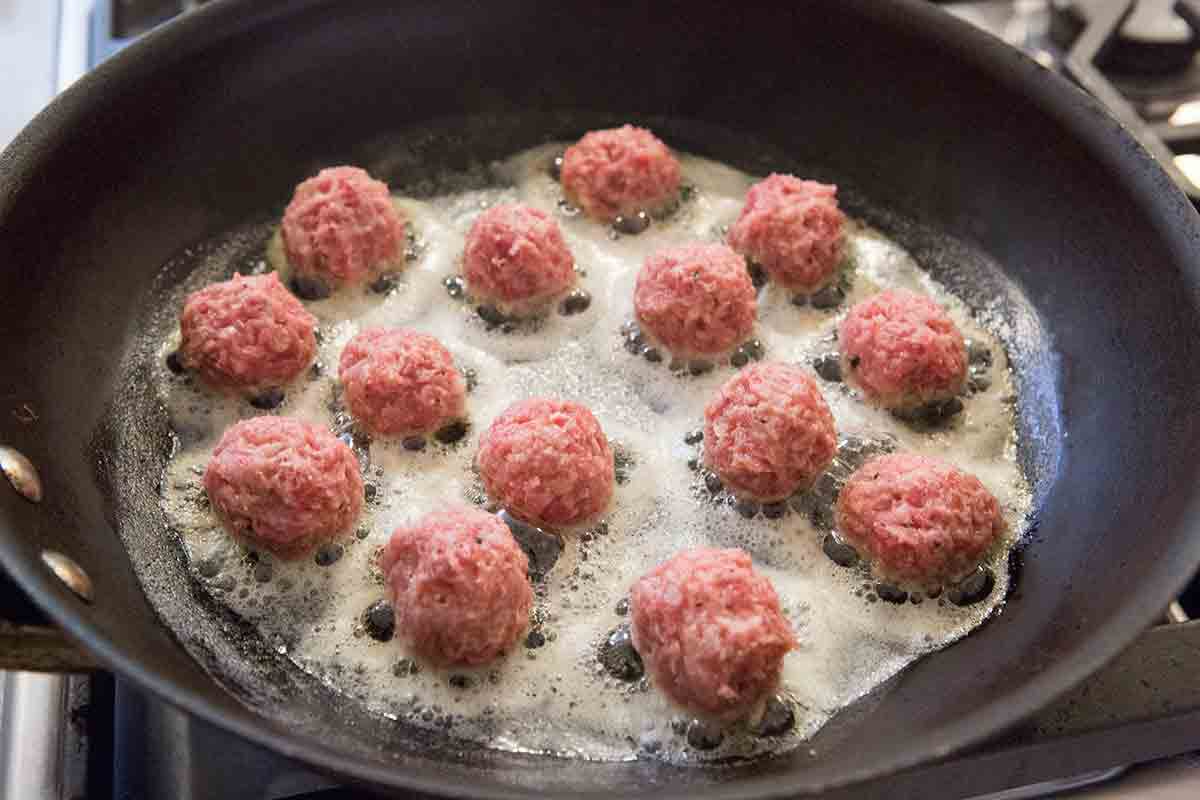 Raw Swedish meatballs cooking in pan with butter 