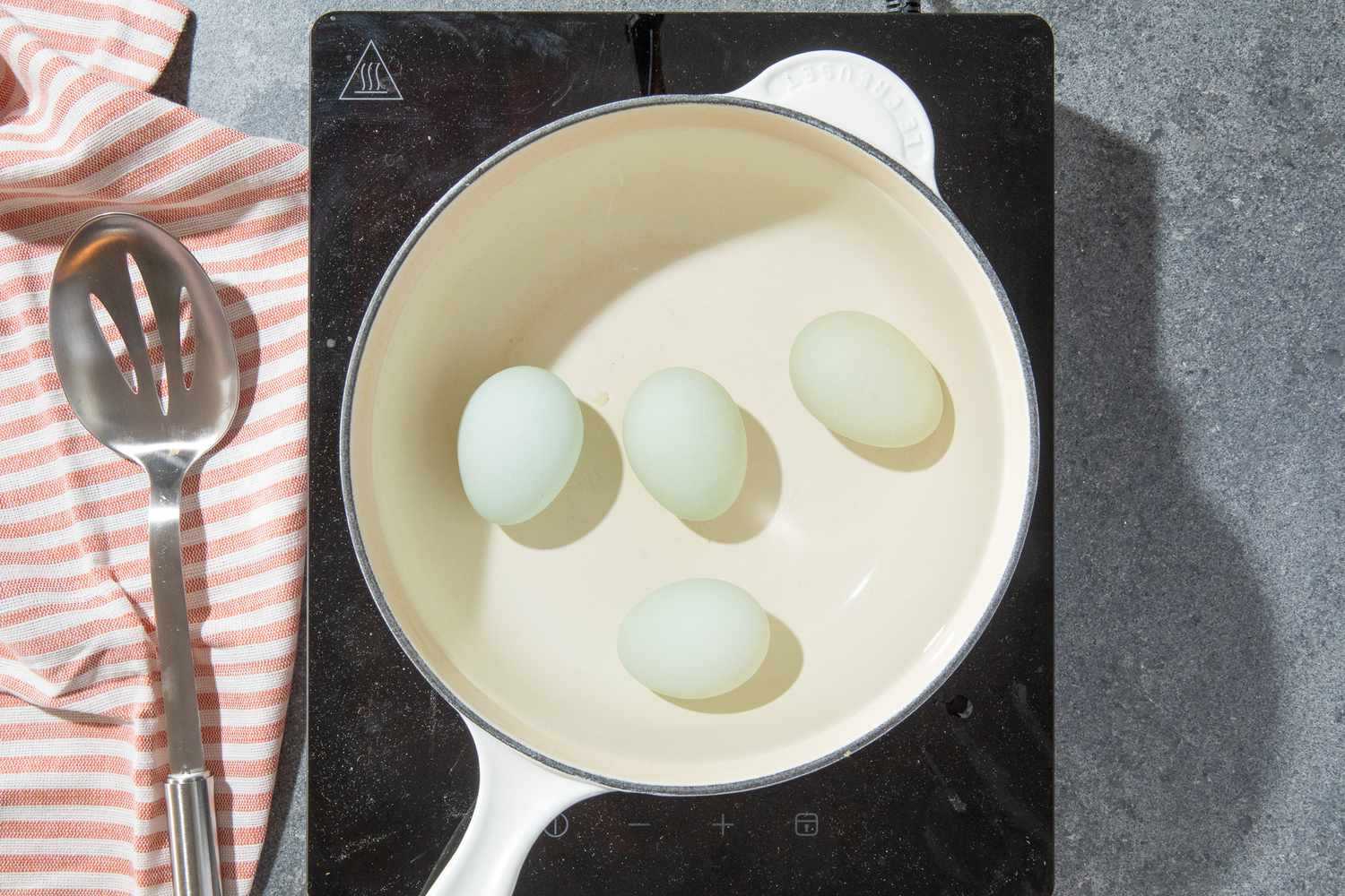 eggs in a pot of water over a portable stove for olivier potato salad recipe