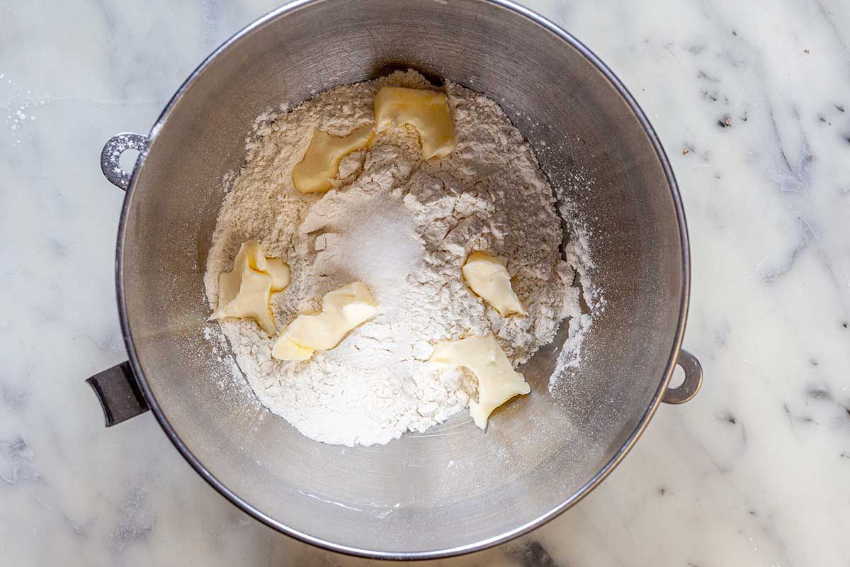Flour, salt and pieces of butter are in the bottom of a bowl for a stand mixer for easy homemade flour tortillas.