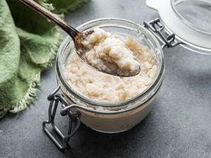 A jar of Homemade Prepared Horseradish with a spoon in it