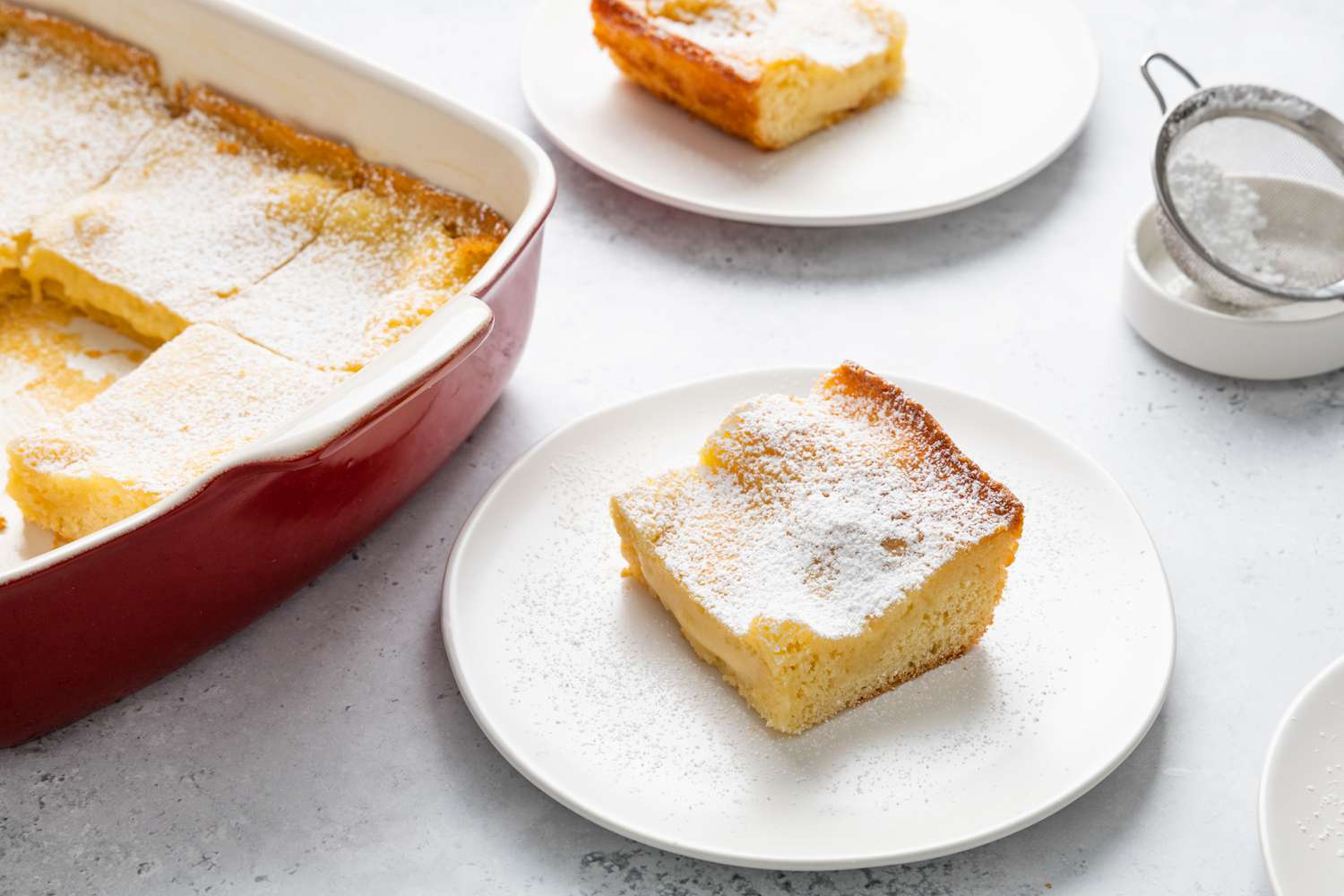 Gooey Butter Cake Slice on a Plate Next to a Baking Pan with More Cake