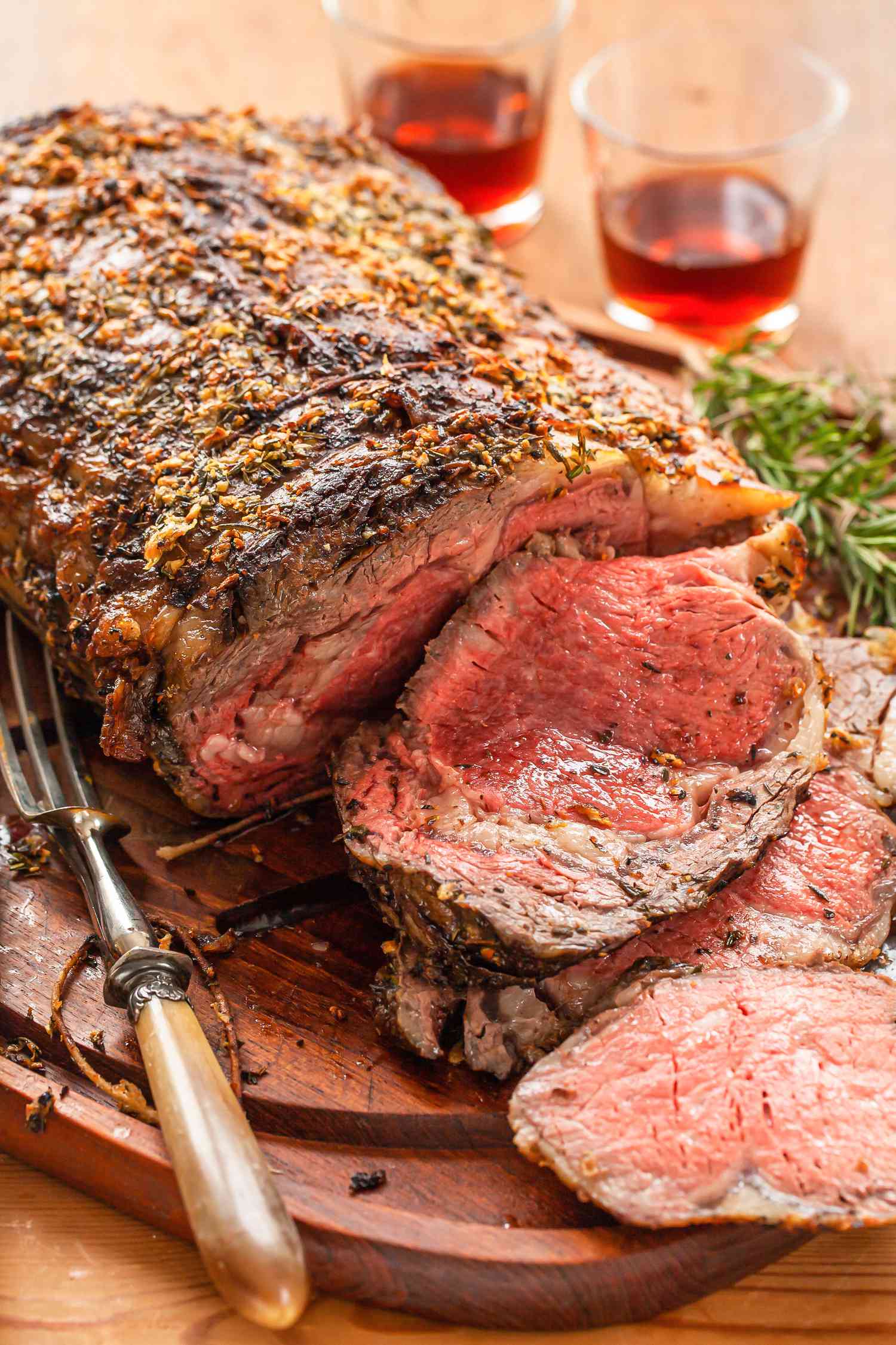 A medium-rare prime rib on a carving board with several slices cut