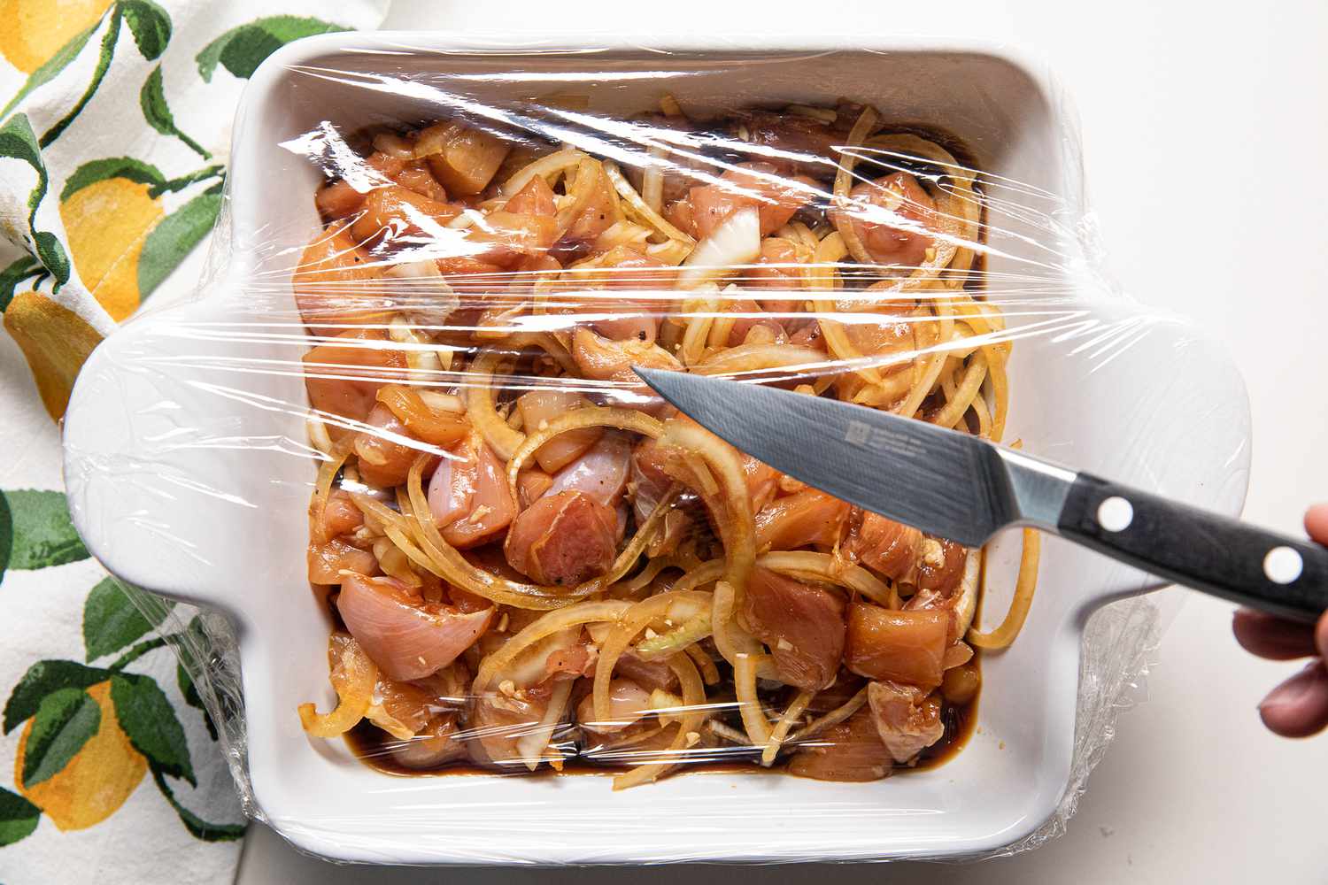 Baking Dish Covered in Plastic Wrap and Holes Poked Into It Using a Knife for Microwave Japanese Chicken and Egg Rice Bowl Recipe