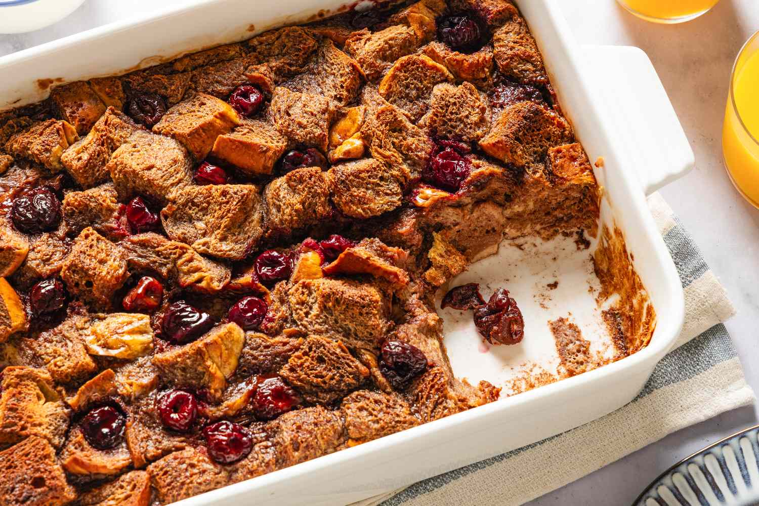 Baked Nutella and cherry French toast in a white dish with some portions missing