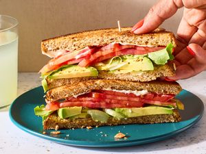 A sandwich with sliced tomatoes, avocado, butter lettuce, and mayonnaise on toasted whole-wheat bread