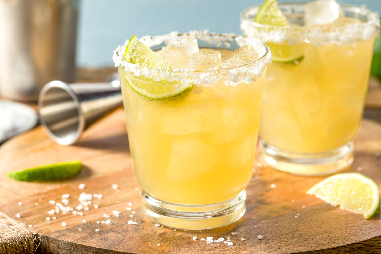 Margaritas on a wooden board with lime wedges and salt