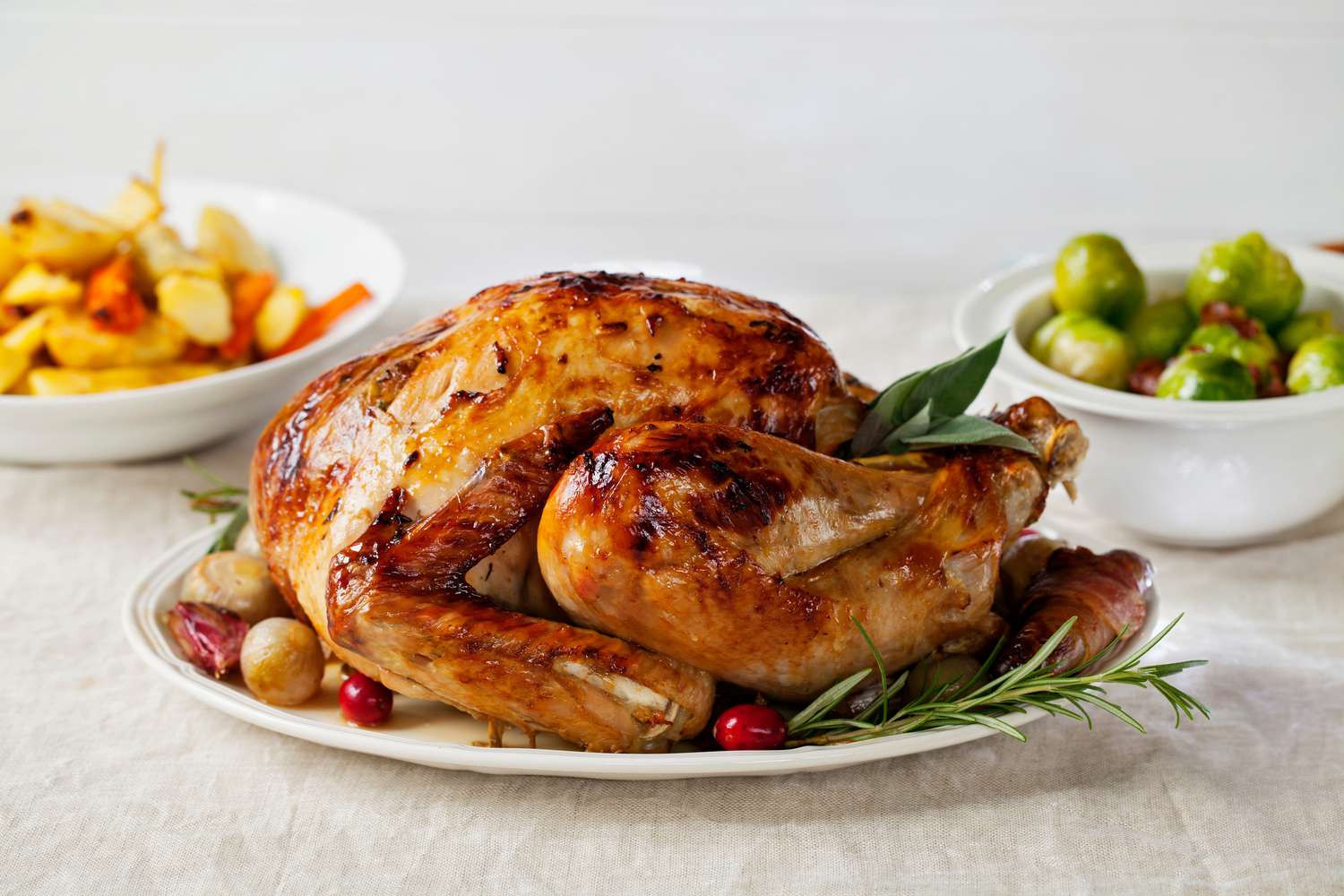 roasted turkey on a platter, veggie sides in bowls in the background