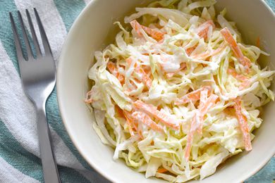 A bowl of coleslaw next to a fork