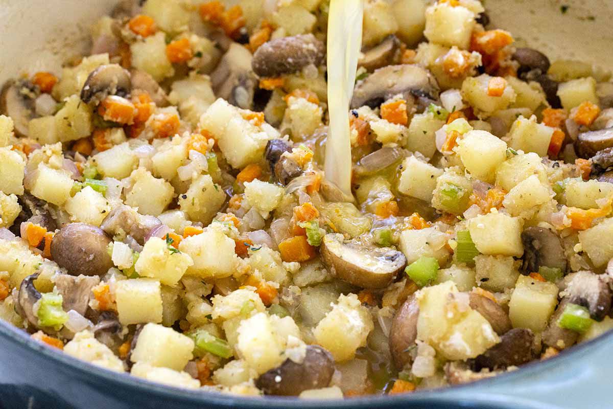 Vegetable pot pie filling of mushrooms, potatoes, carrots and celery cooked in a skillet.