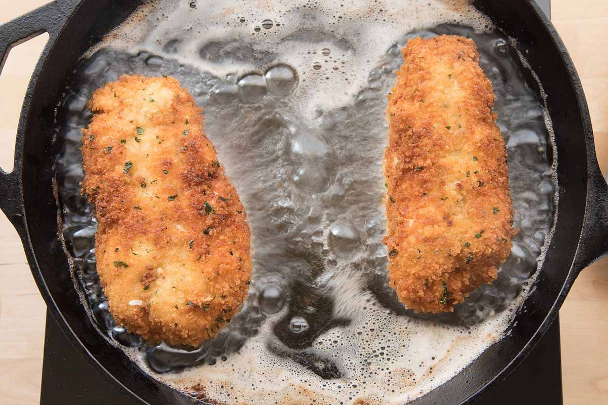 Easy Chicken Crodon Bleu being fried in butter in a black cast iron skillet.