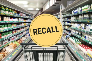 Supermarket aisle with a shopping cart in the foreground and a recall warning sign displayed prominently