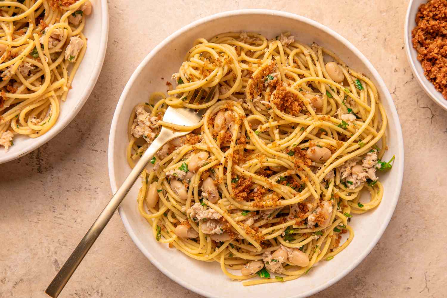 Pasta with tuna, white beans, and breadcrumbs in a bowl with a fork.