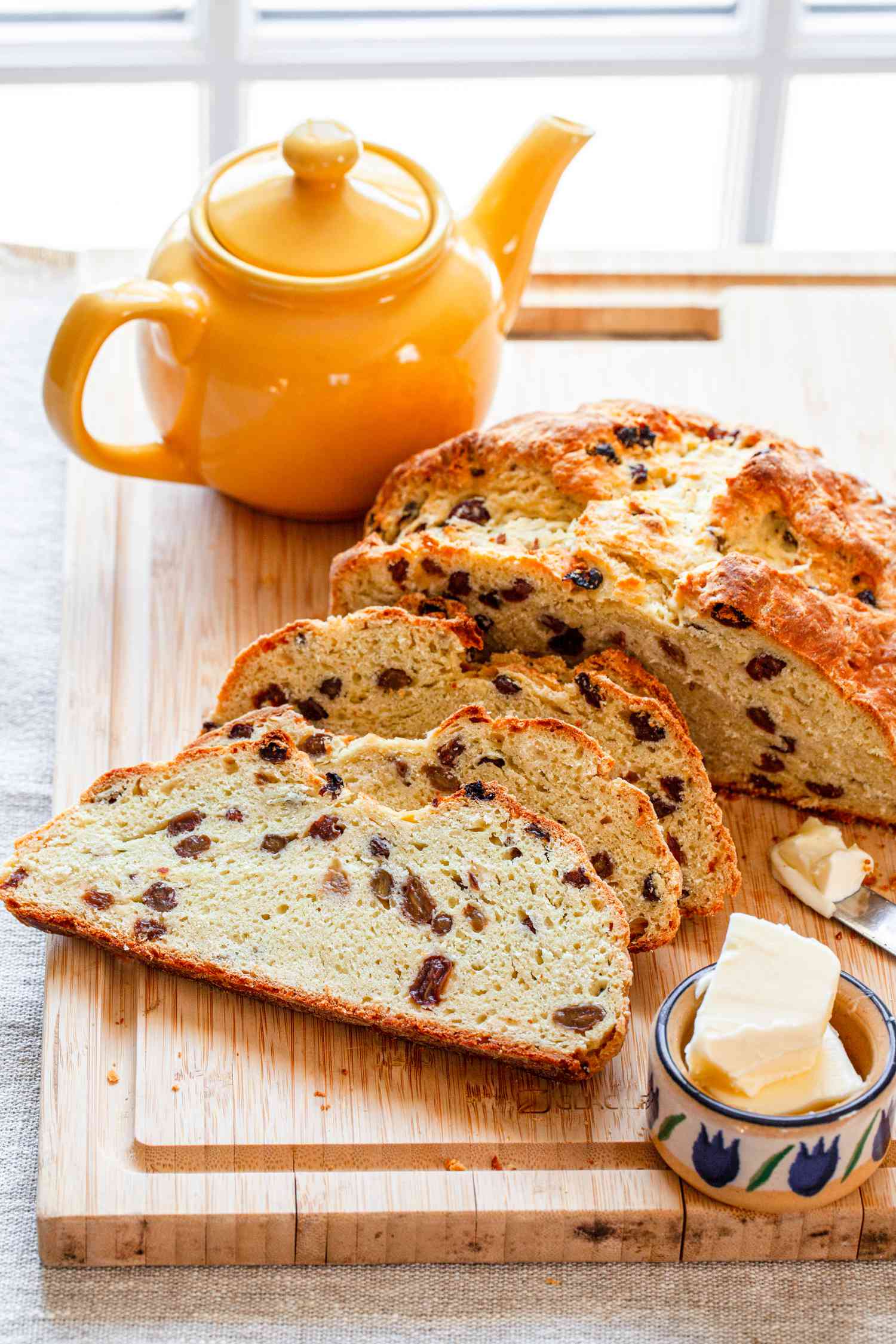 A Loaf of sliced Irish Soda Bread on a table with a pot of tea