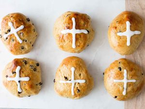 Homemade Hot Cross Buns on a surface with sugar crosses piped on top