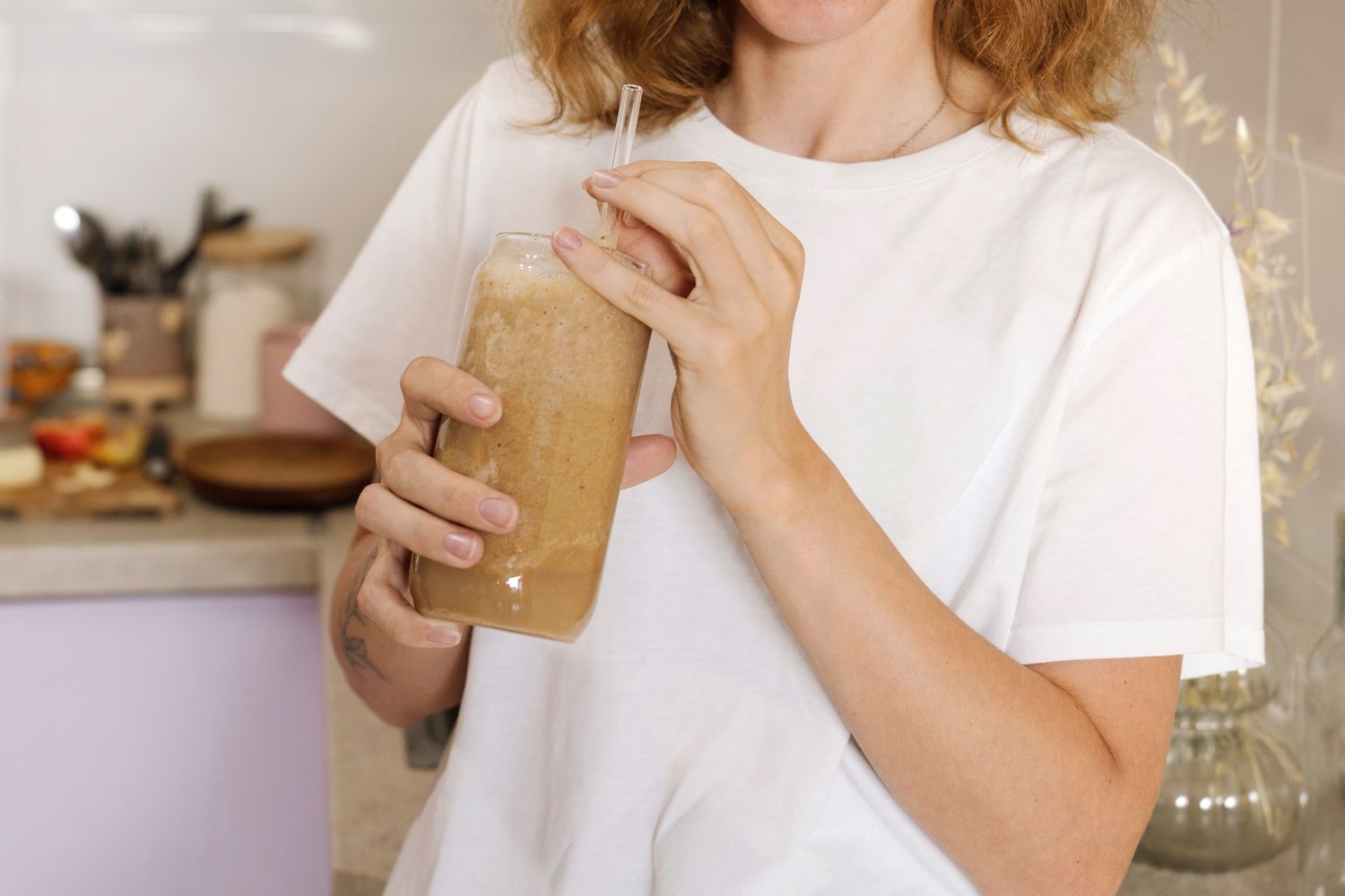 Person holding a smoothie in a kitchen setting
