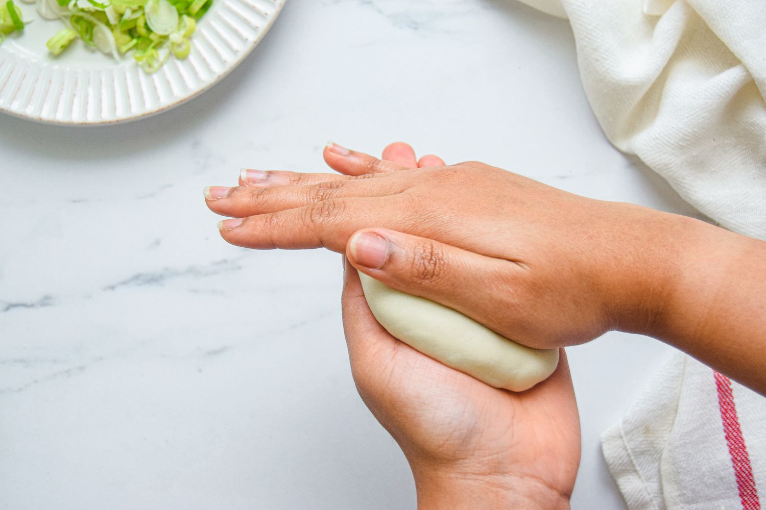 Flattening spiral scallion pancake dough in between hands.