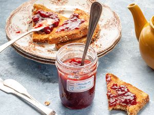 Strawberry Jam Surrounded by Toast on Plate, Utensils, and Tea Pot on Table