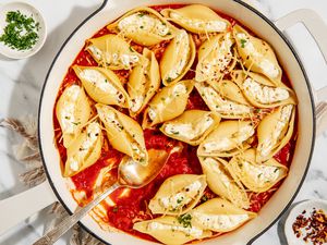 Stovetop Stuffed Shells in a large pan with a large serving spoon - small dish with crushed red pepper and small dish with chopped parsley