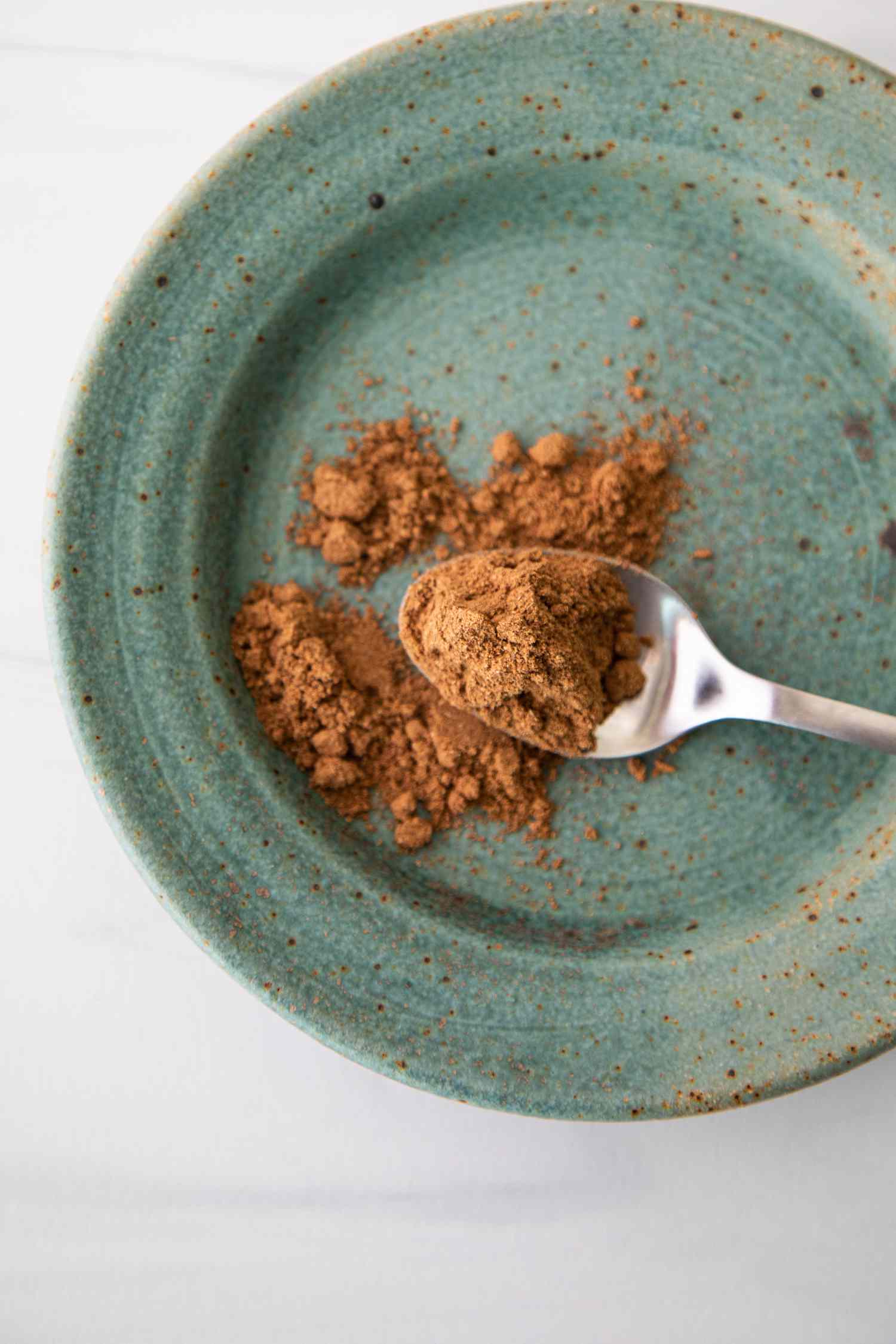 Chinese Five Spice on a Spoon with Some Overflowing onto a Plate