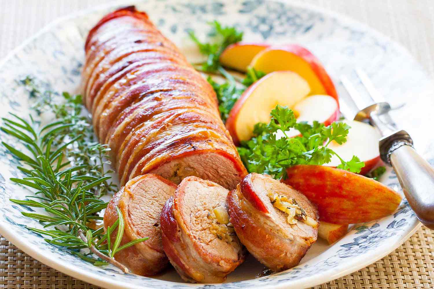 bacon wrapped pork loin served on platter with apples