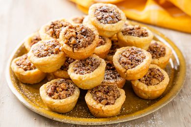 Stack of pecan pie cookies on a plate with a mustard colored table napkin in the background