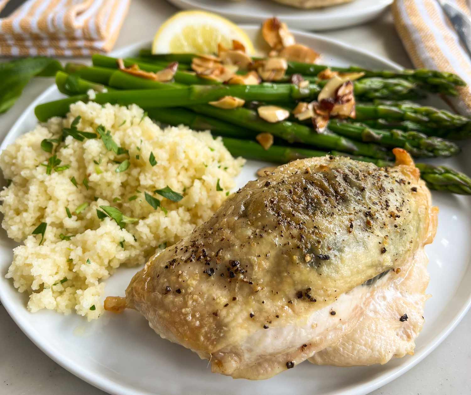 A plate with roasted chicken, couscous, and asparagus