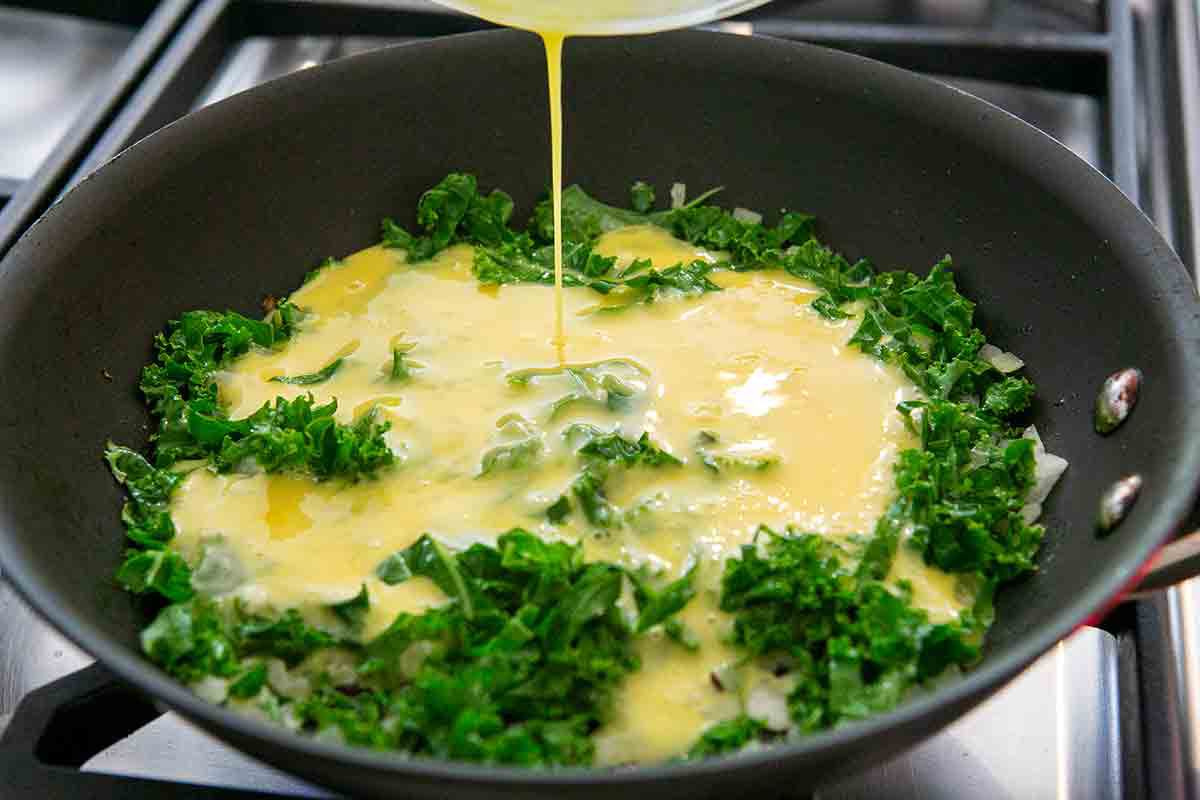 add beaten eggs to kale in pan