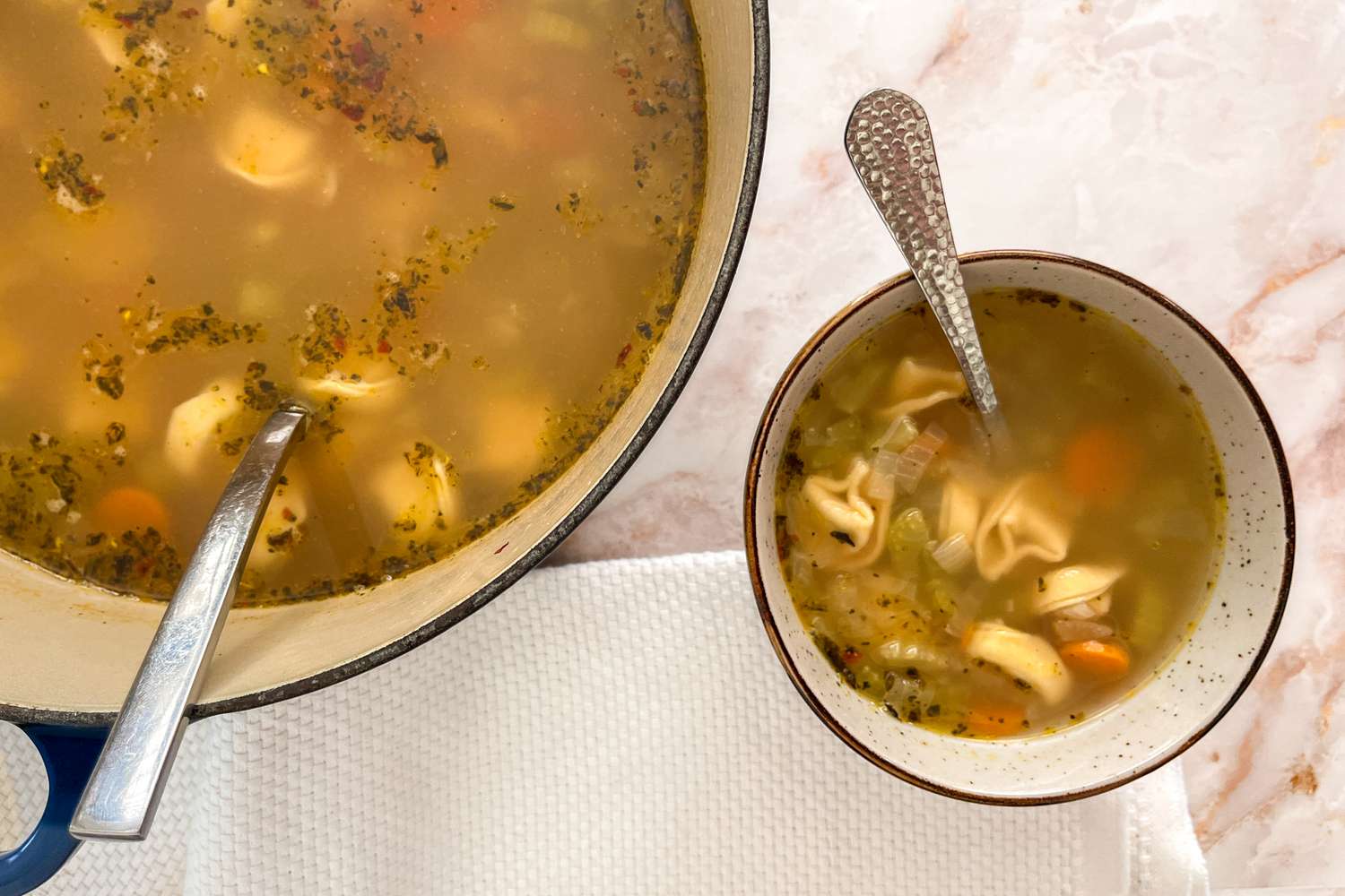 Bowl of 30-minute tortellini soup next to a Dutch oven with more