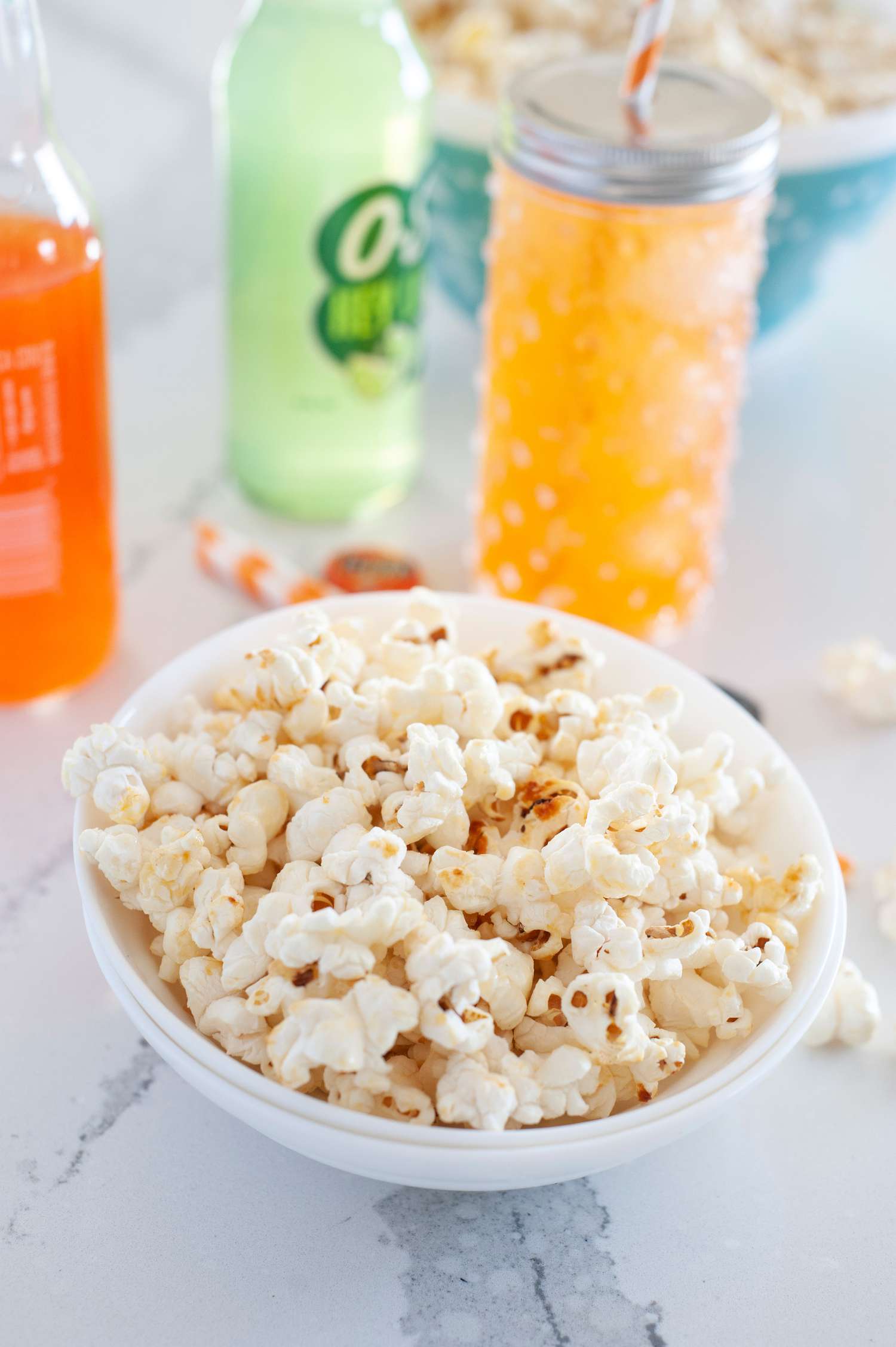 A bow of kettle popcorn set in front of orange sodas.