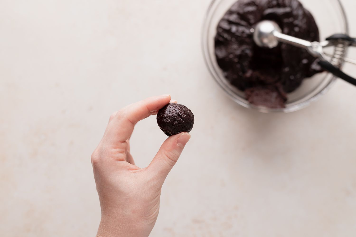 Rolling dough for chocolate crackle cookies into a ball.