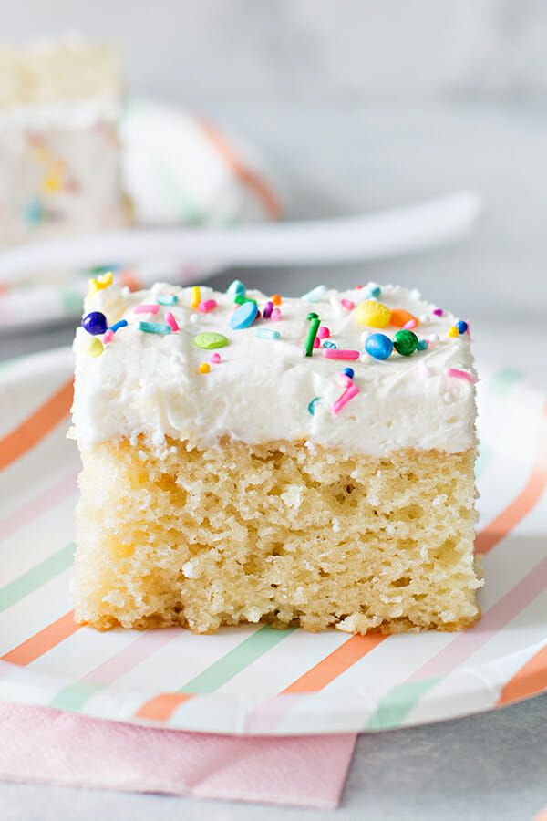 crowd pleasing Vanilla Sheet Cake Recipe - slice of frosted vanilla cake with sprinkles