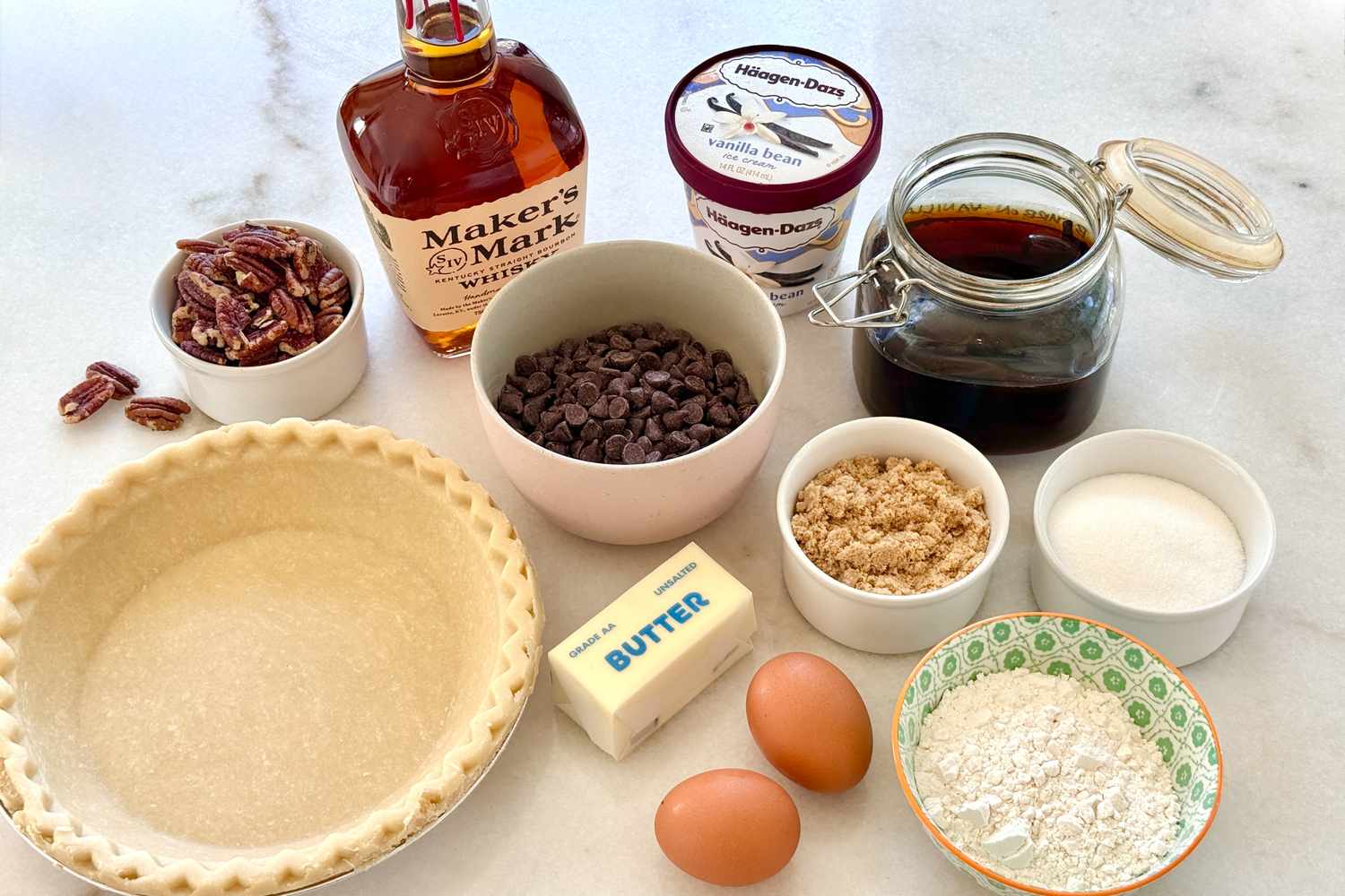 Ingredients for a bourbon pie recipe including a pie crust pecans bourbon chocolate chips eggs butter sugar and vanilla ice cream