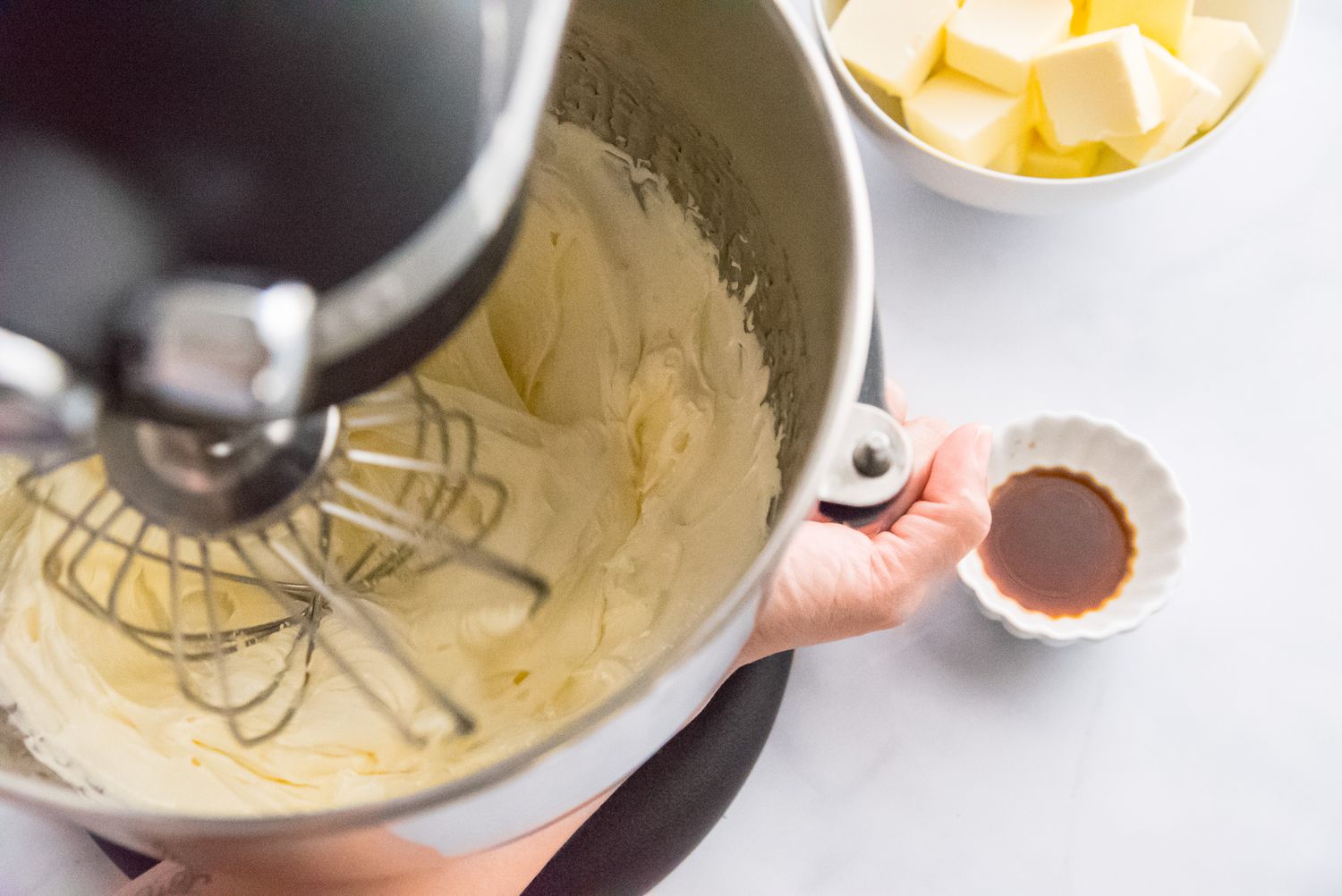 Whisking egg yolks and sugar syrup in a stand mixer to make a French buttercream frosting recipe.