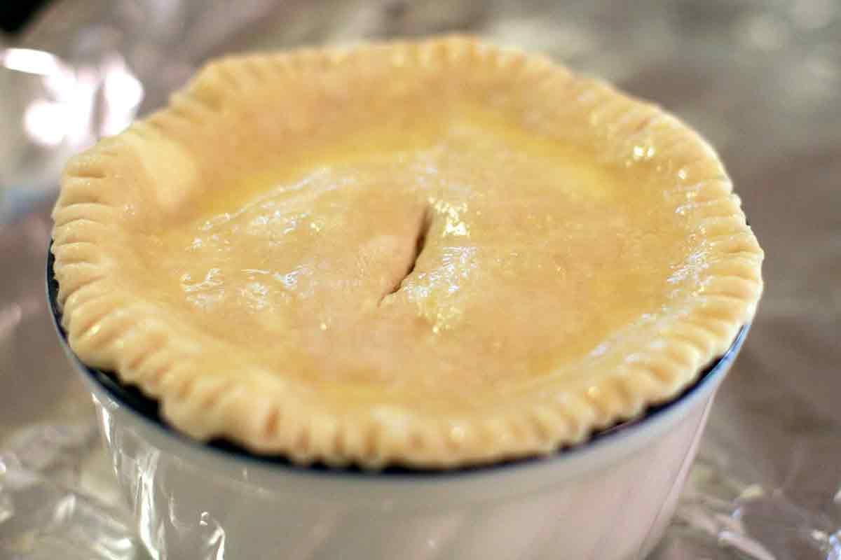 Chicken pot pie with a pastry crust on top and a slit in the middle.