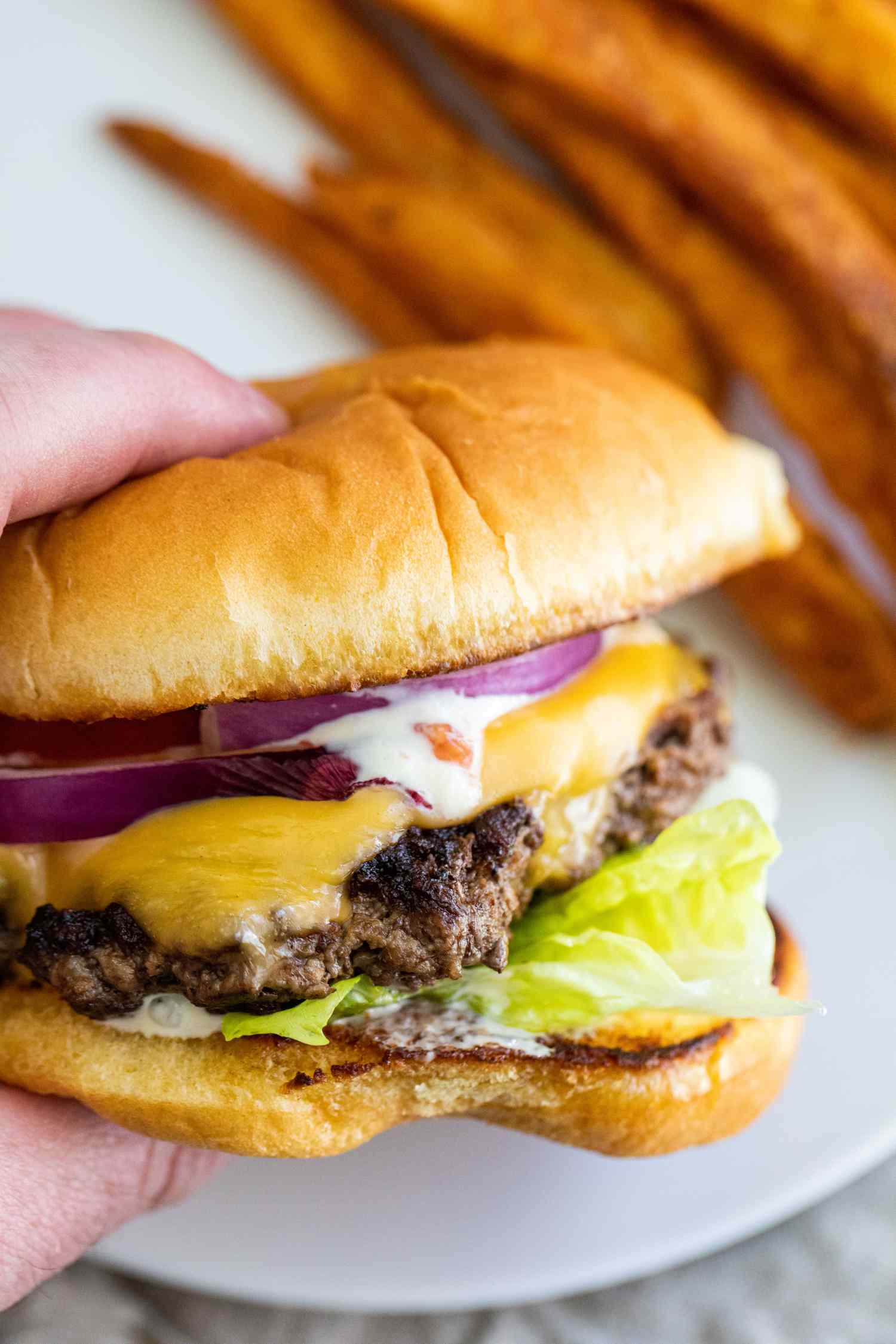 A hand holding a homemade smashburger.