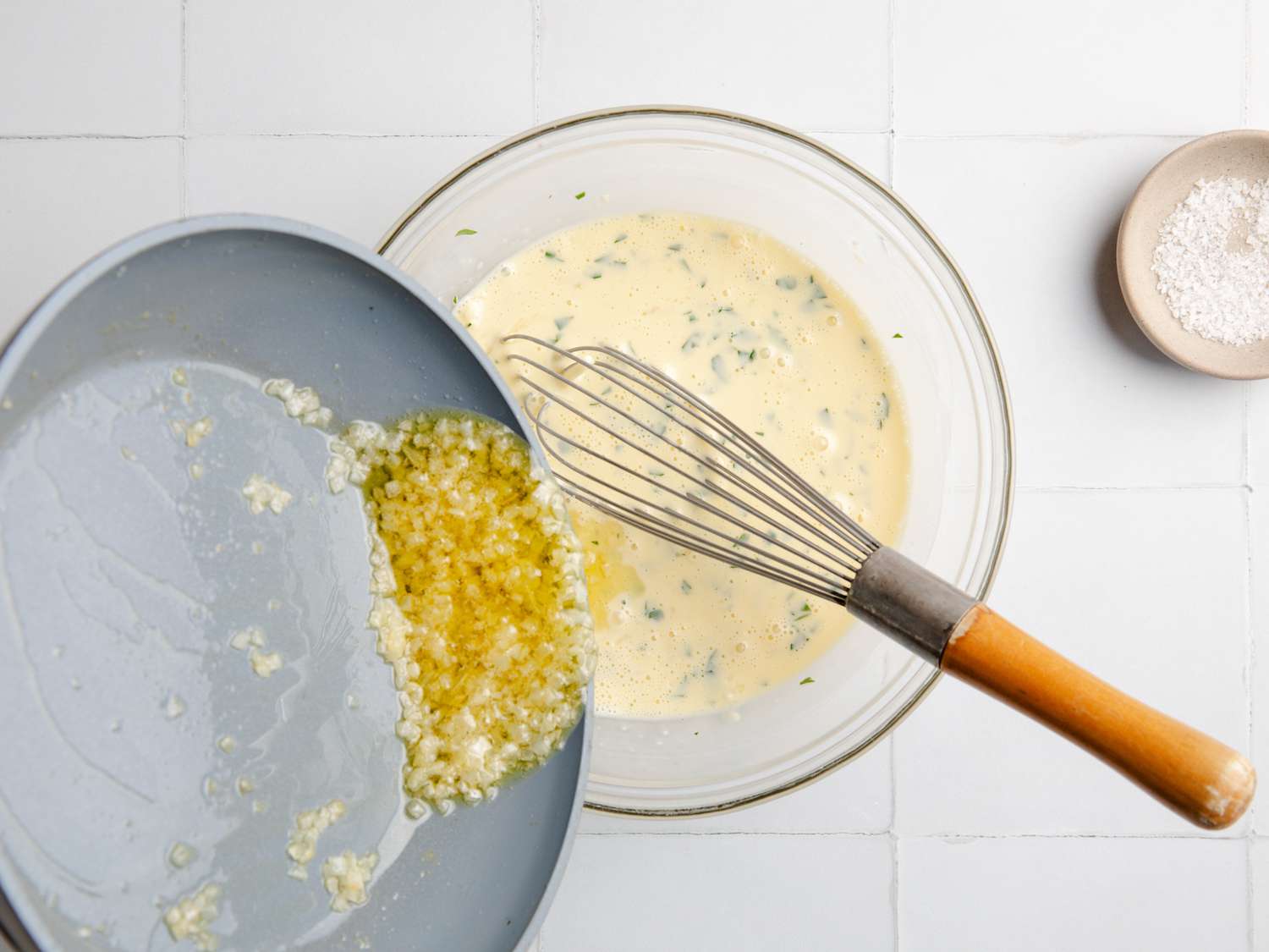 pouring liquid garlic butter into a bowl of sauce