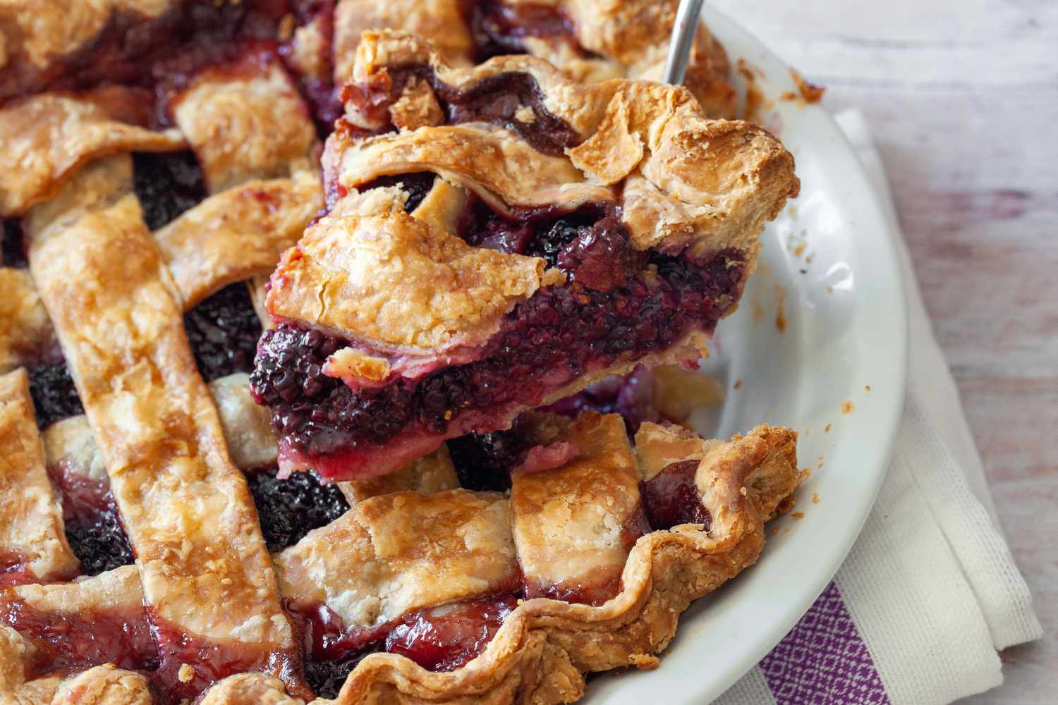 Blackberry Pie in a Pie Dish with a Slice Raised on a Pie Server